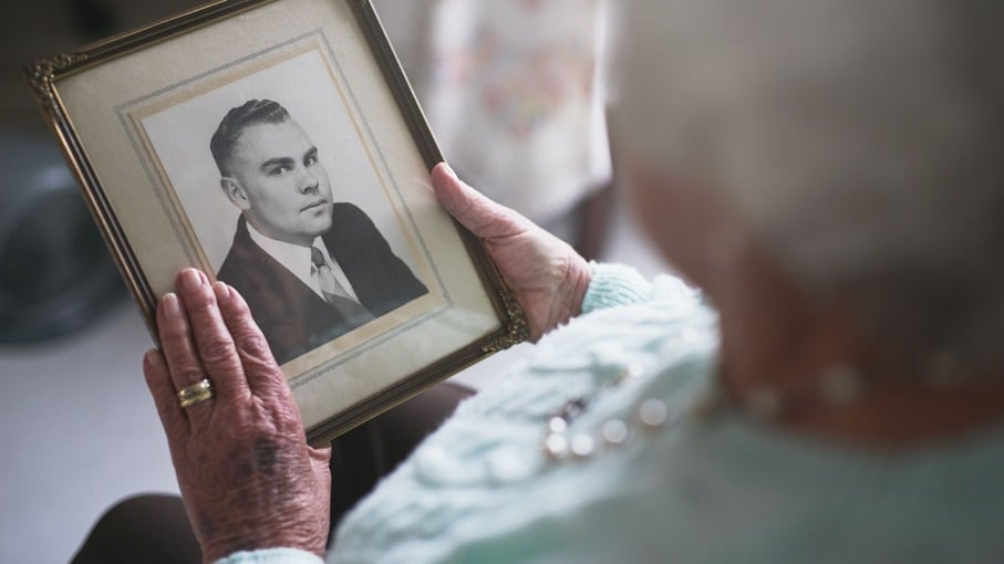 Mulher idosa olhando para uma foto antiga de seu marido